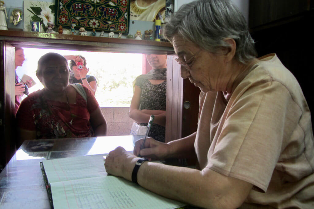 Sister Lucia records embroidering work in a pay ledger at St. Mary's Mahila Shikshan Kendra in India