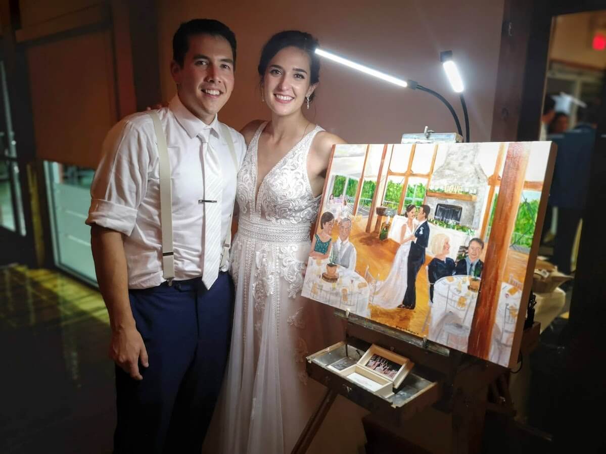 Newlyweds pose with a painting of their first dance by Emily McDougall.